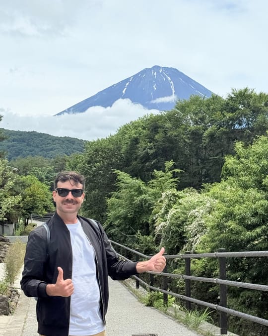 Kris giving two thumbs up on a path, with Mount Fuji behind him.