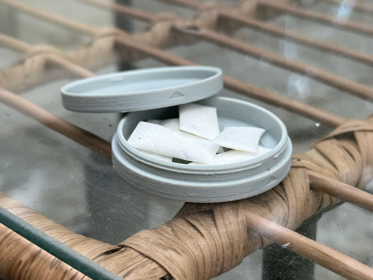 A gray 3D-printed Mini MagSafe Zyn Container on a glass patio table